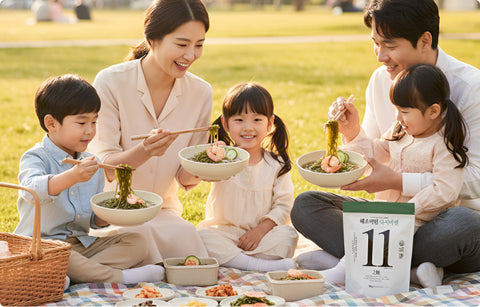 a family eating haechomiin noodles together at the park